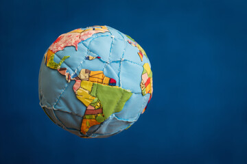 Fototapeta premium Patchwork Fabric Globe; Whimsical, Colorful World Map; Blue Background; Global Concept; Handmade Textile Art.