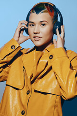 young woman with colorful hair wearing headphones and a bright yellow jacket, posing confidently...