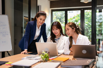 Confident mature business professional woman talking to younger female colleague at office table,...
