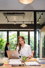 Asian business woman using laptop computer typing And working online sitting at desk in office ....