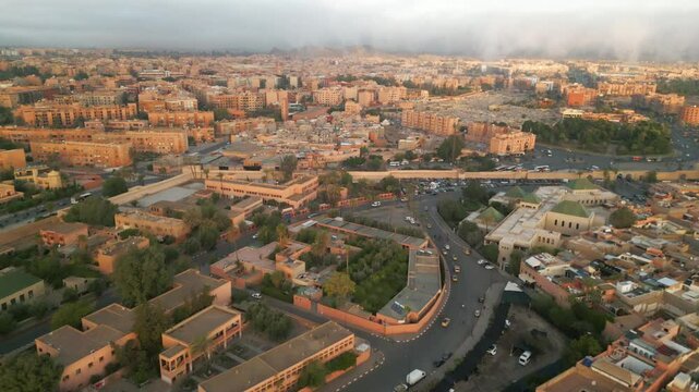 Aerial panoramic view of Marrakech city at sunrise with soft morning light illuminating terracotta buildings and streets in Morocco