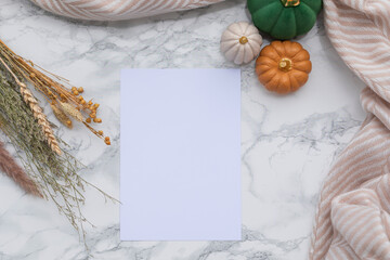 Festive fall composition with empty sheet of paper, golden pumpkin decor, green and beige tones on...