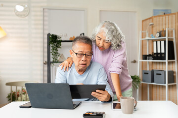 Senior old couple holding documents reading paper bills paying bank loan online, calculating...