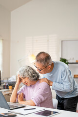 Senior couple checking bills and calculating expenses using a calculator at home, debt taxes and...
