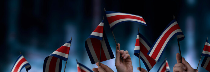 Costa Rica flags in their hands on a blurred urban background