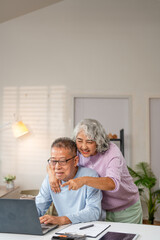 Senior Spouses enjoying retirement and free time browsing on laptop  At Home. Older Couple Browsing...