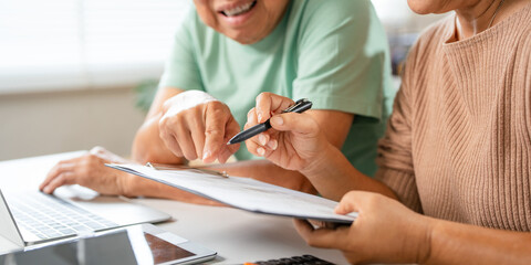 Happy senior couple using laptop counting taxes refund receipts to save money at home. Old man and...