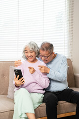 Happy 60s older couple holding  mobile phone video conference calling by social distance virtual...