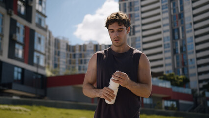 Caucasian man athlete male guy sport drinking bottle water refresh workout city outside fitness...