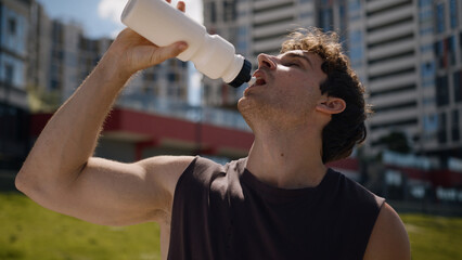 Caucasian man athlete sportsman sport male drinking water bottle thirst breathing hard workout...