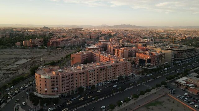 Aerial panoramic view of Marrakech city at sunrise with soft morning light illuminating terracotta buildings and streets in Morocco