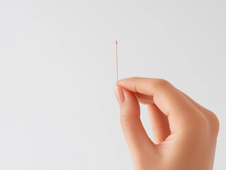 Hand holding tiny contraceptive implant on white