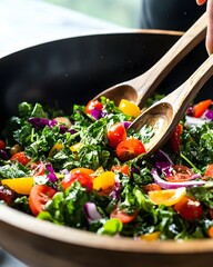 Bowl of salad with a person holding a pair of tongs