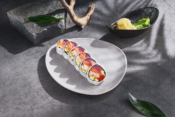 Salmon, tuna, and shrimp roll in daikon on stoneware plate, bright sunlight, overhead composition