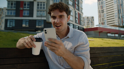Caucasian man drink coffee holding cup mobile phone smartphone bad news loss bet male guy...