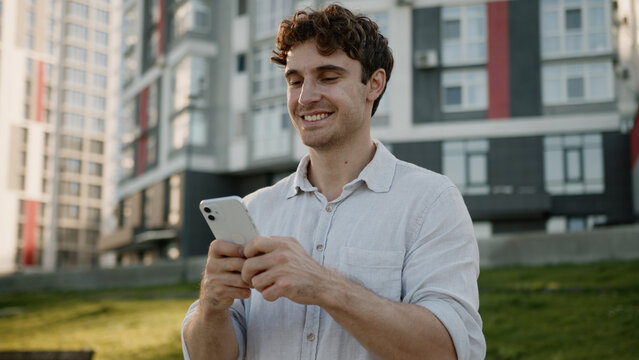 Confident Caucasian young man holding mobile phone smartphone businessman outdoor guy searching location at city looking around town male online internet GPS navigation cellphone business app gadget