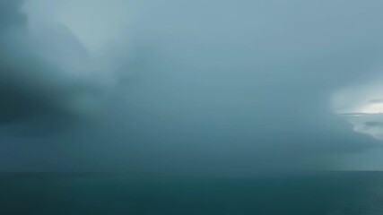 Dark thunderstorm clouds unleashing cascading rain onto a restless ocean beneath a brooding sky, dramatic seascape capturing nature’s raw power with churning waves and moody lighting on the open sea