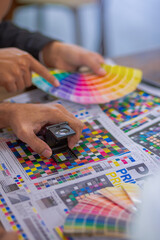 Team graphic designer checking print quality of media graphics proof print and color guides in printing industry. Selected focus