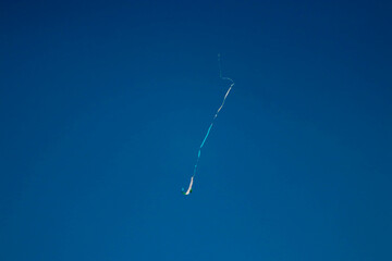 Kite Flying High in a Clear Blue Sky with Long Trailing Tail	
