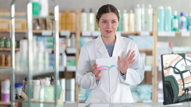 Smiling polite female pharmacist white coat standing at drugstore counter, holding box of pills and suggesting as suitable over-the-counter solution for common symptoms