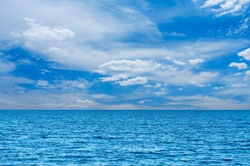 Enjoy the calm of the ocean beneath a bright blue sky with fluffy clouds. This peaceful seascape...