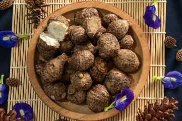 Organic farm‑to‑table produce in flat lay view, freshly steamed taro roots styled with blue flowers and pine cones.
