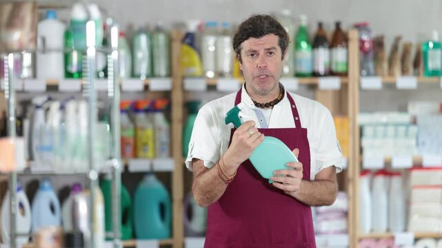 Man seller advertises glass cleaning spray, demonstrates new product from well-known manufacturer. Store employee suggests paying attention to product . High quality 4k footage
