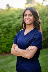 Multiethnic nursing student standing outside wearing her scrubs and looking at the camera. Attractive female medical student photo