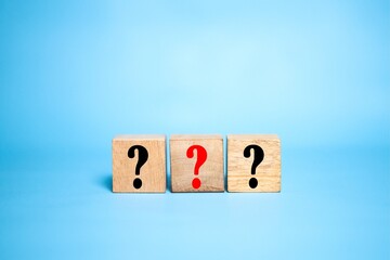 Question mark symbol. Question mark concept word on wooden cube. Light blue background.