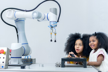 Kid female teen child enjoy Machine Learning Robot arm is Moving Under Control robot at technology class, stem education robot arms for digital automation software for artificial intelligence ai