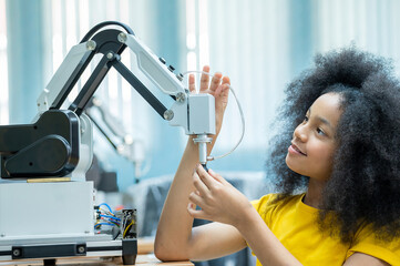 Kid female teen child enjoy Machine Learning Robot arm is Moving Under Control robot at technology...