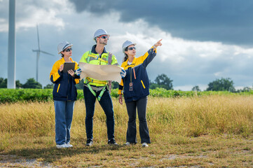 Team of Engineers Planning Project for Renewable Energy Professional Team Inspecting Wind Turbines for Clean Energy Generation Collaboration : Engineers with Blueprint at Wind Farm.