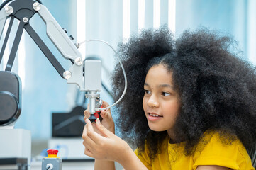 Kid female teen child enjoy Machine Learning Robot arm is Moving Under Control robot at technology class, stem education robot arms for digital automation software for artificial intelligence ai