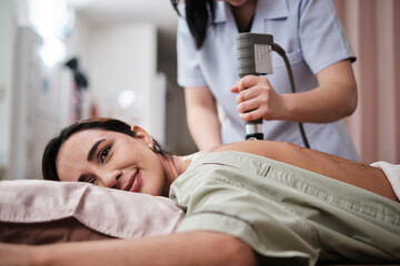 A female Latino patient recovered treated with gel ultrasound device for back pain relief procedure...