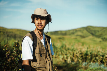 Young Southeast Asian male hiker looking away in green hills