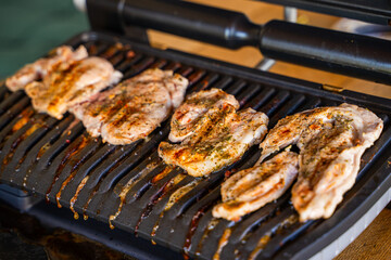 Pork steak being grilled on an electric grill, close-up