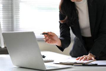Close up of businesswoman pointing at laptop screen during financial report review