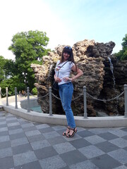 Woman near a fountain that flows from a large stone, tourism