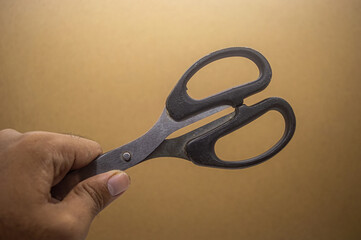 Hand gripping black scissors against a plain backdrop, emphasizing control, sharpness, and minimalist style. Ideal for craft, work, and everyday cutting tools in clean visuals