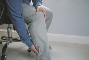 Businessman sitting on a chair for a long time causing knee pain