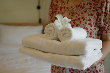 A beautiful housekeeper holding towels to prepare in a luxury hotel room, preparing for the travel...
