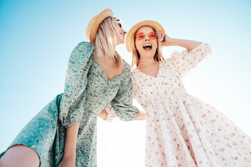 Two young beautiful smiling hipster woman in trendy summer dress. Carefree women in the street in...