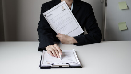 Businesswoman employer sitting holding new employee's documents to evaluate and review new...
