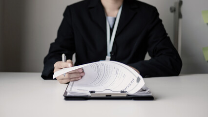 Businesswoman employer sitting holding new employee's documents to evaluate and review new employee's personal history. Recruitment concept, job placement
