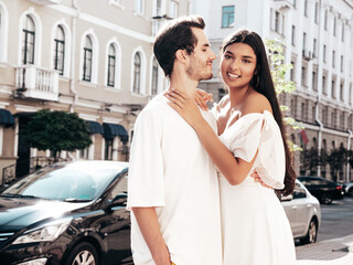 Fototapeta premium Smiling beautiful woman and her handsome boyfriend. Happy cheerful family. Sexy couple posing in the street at sunrise. During romantic date at sunny summer day outdoors. Looking at each other