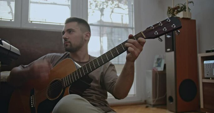 A diverse group of musicians shares a creative afternoon playing a guitar. The friends enjoy leisure time, performing music.