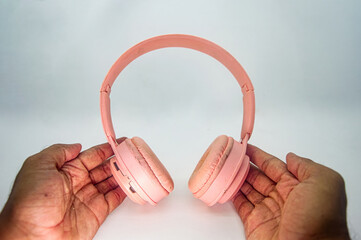 Hands holding pink wireless headphones above clean white background, emphasizing soft texture, modern design, and everyday audio lifestyle. Perfect for tech, music, and fashion visuals