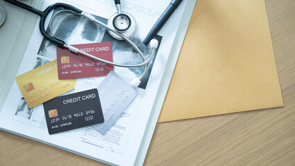 Hand holding a gold credit card over medical records and stethoscope, hospital payment scene.
