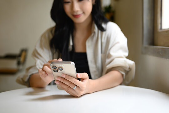 Close up of a woman hands holding and using a smartphone while seated at a cafe table