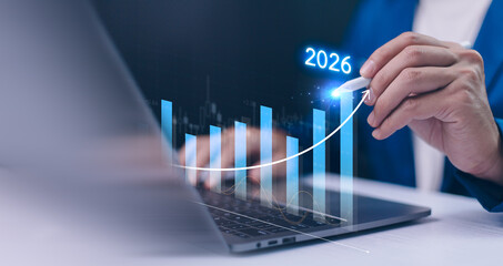 Businessman uses a stylus to draw a holographic growth arrow a bar chart on a laptop, forecasting...